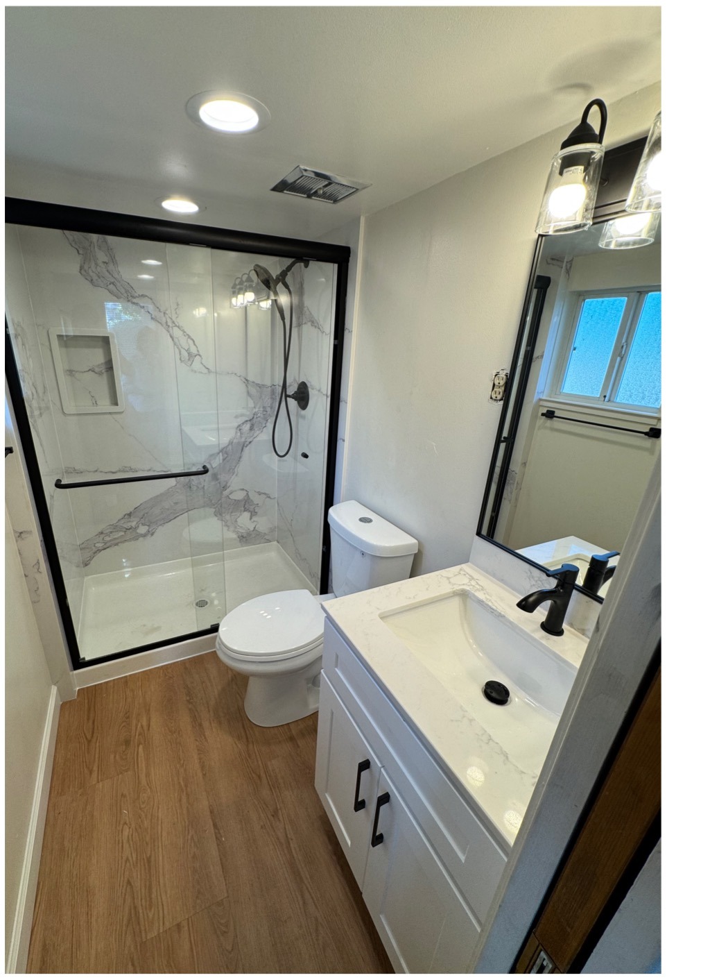 Bathroom remodel after with finished shower, vanity, lighting, and flooring
